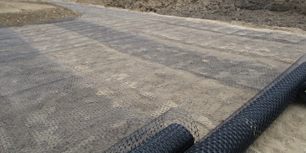 The machine is dumping soil onto the geogrid.
