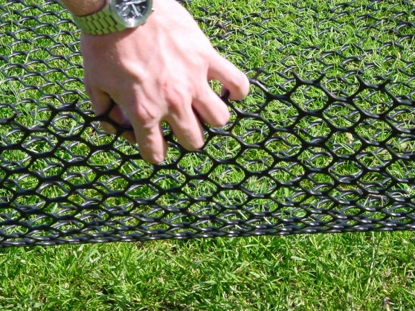 A hand reveals the lawn reinforcement net.