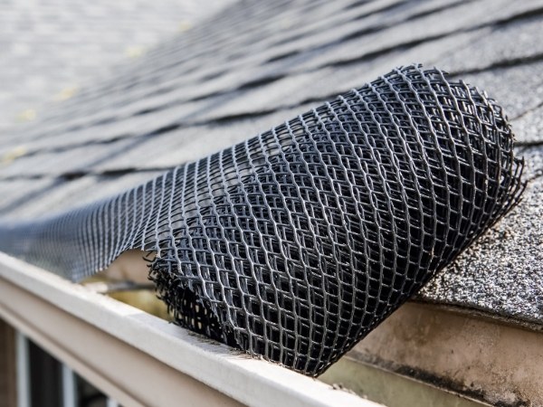 A roll of plastic mesh gutter guard is installed on the gutter.