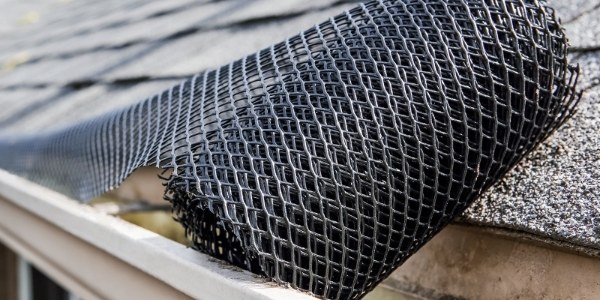 A unrolled plastic mesh gutter guard is placed on the gutter.