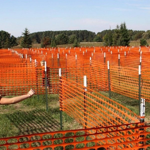 Kids are playing in a maze made of orange safety mesh.