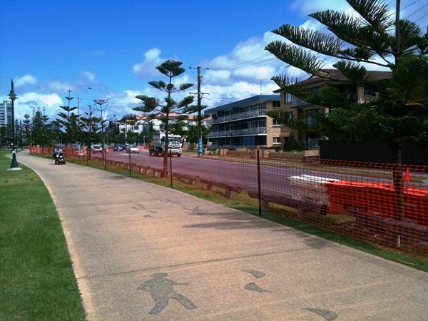 Safety barrier mesh is set up between sidewalk and the road.