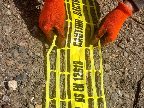 The worker is laying the underground warning mesh.